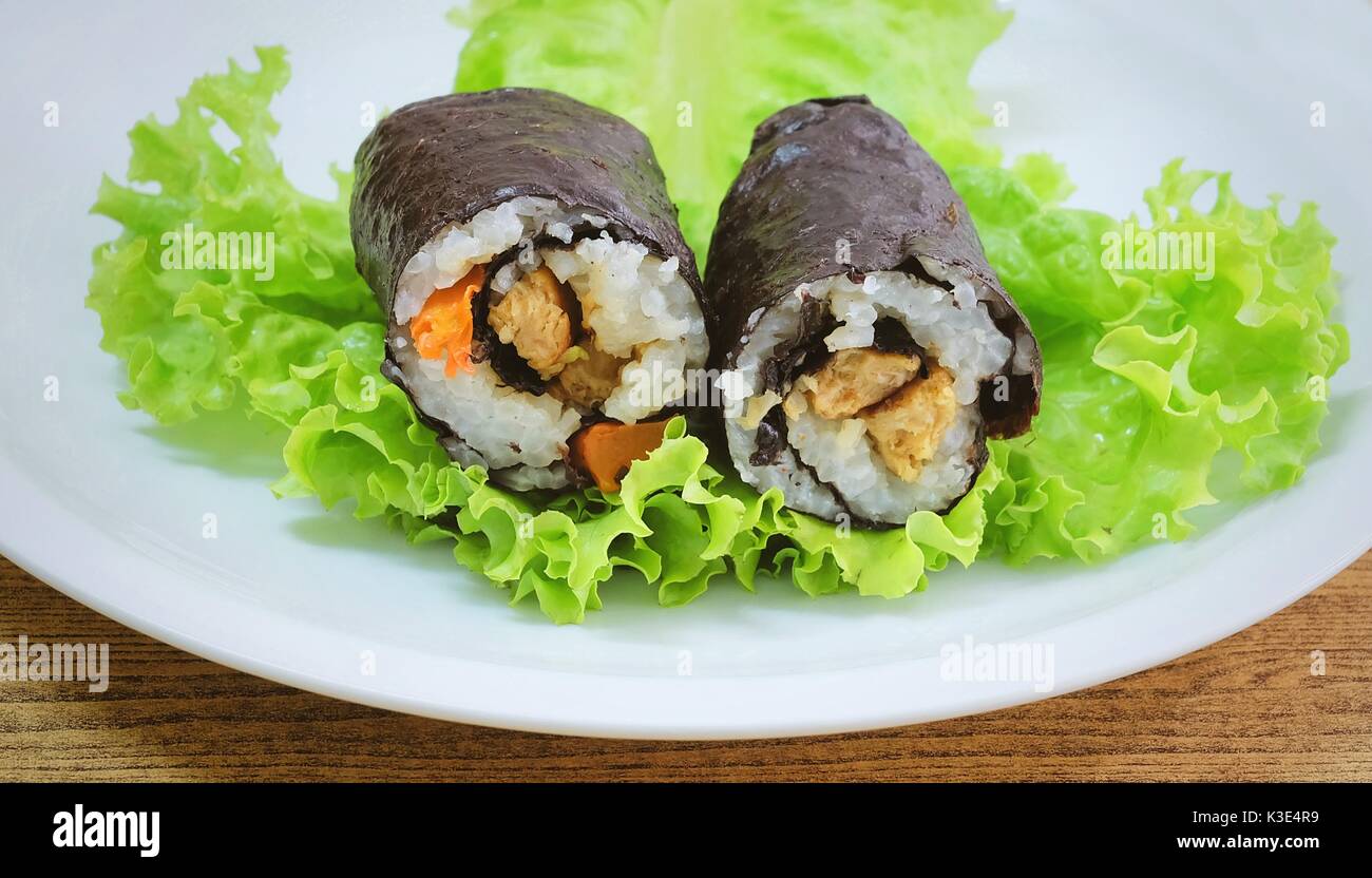 Japanische Küche, Traditionelle Vagetarian Japanischen Reis Maki Sushi Roll Material mit Tofu und Karotte eingewickelt in Nori Algen serviert auf grünen Eichen. Stockfoto