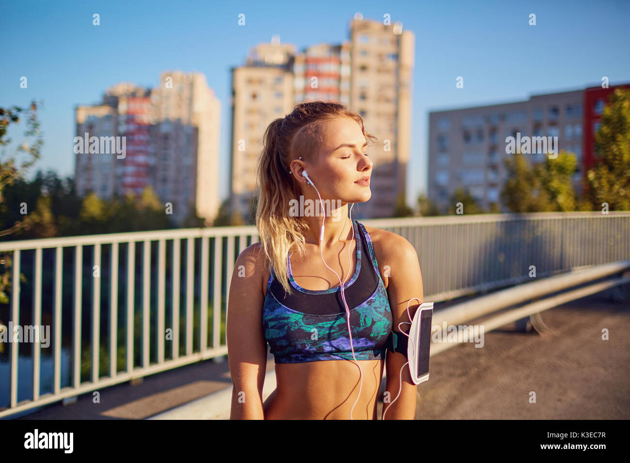 Ein Mädchen läuft in Kopfhörer auf einer Brücke in der Stadt in der morn Stockfoto
