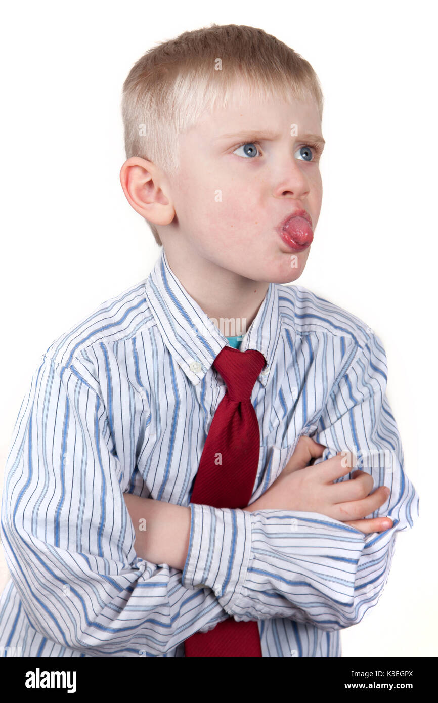 Little Boy in Hemd und Krawatte Stöcke, seine Zunge, kreuzt die Arme. Stockfoto