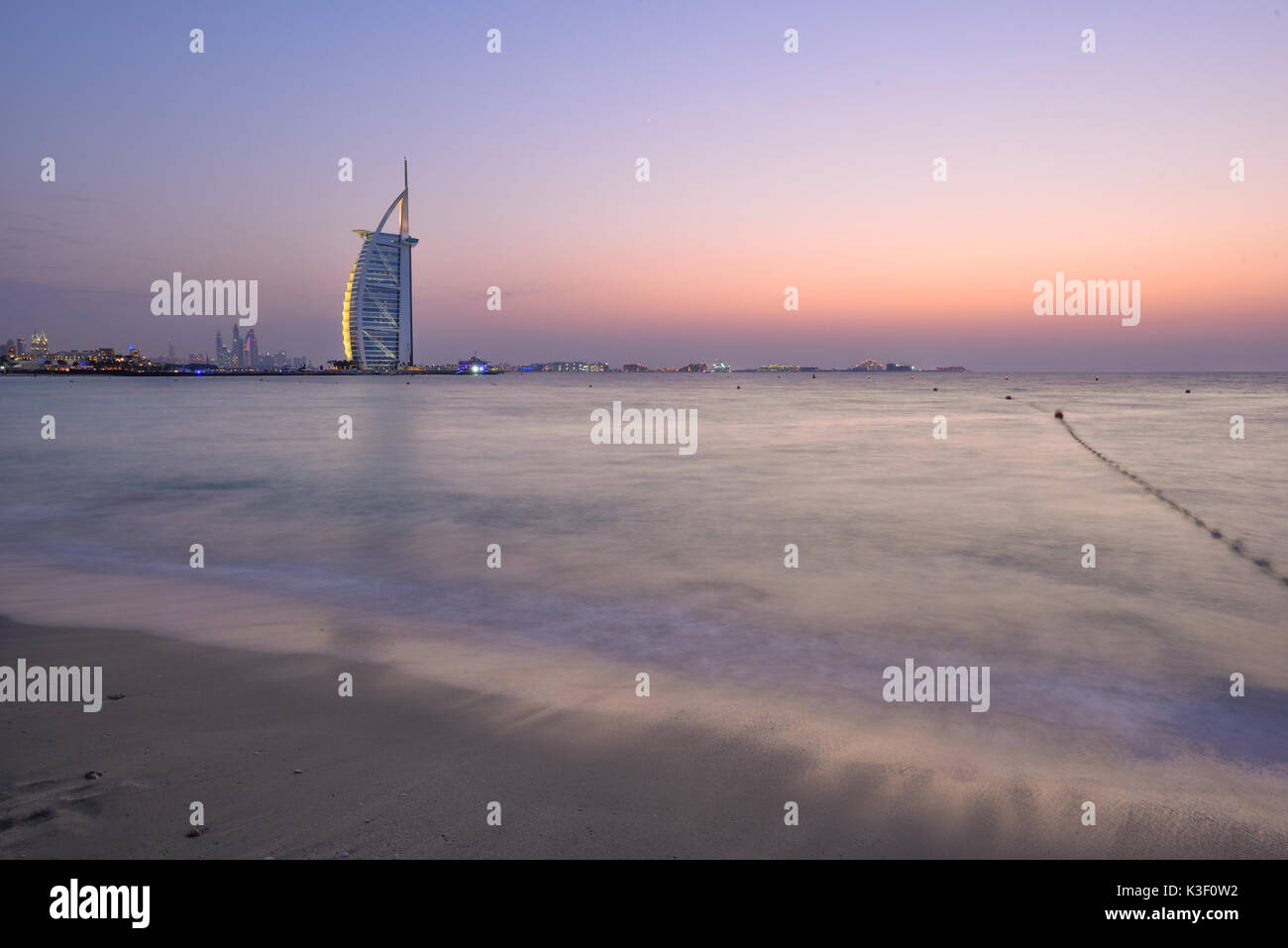 Dubai, Vereinigte Arabische Emirate - 10.Oktober 2016: Die beleuchteten Burj Al Arab Hinweis und in der Abenddämmerung marinal, Ansicht von Jumeira Beach, nach Südwesten. Stockfoto