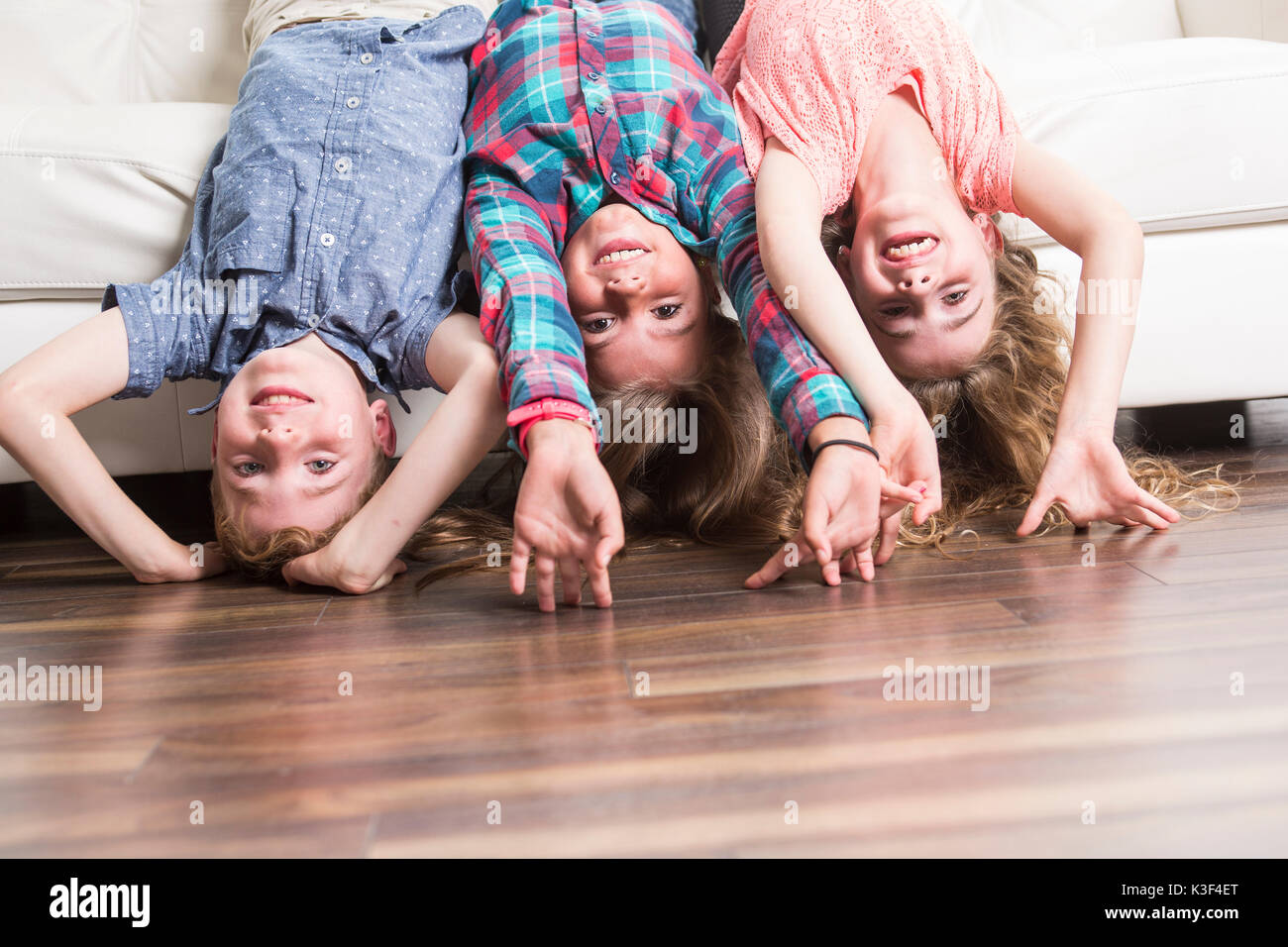 Drei Kinder mit der Oberseite nach unten auf einem weißen Sofa zu Hause Stockfoto