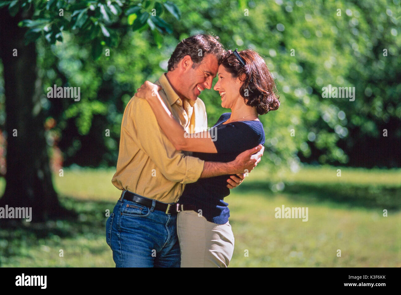 Lachend ein paar Umarmungen im Garten Stockfoto