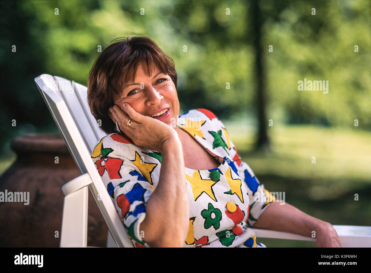 Portrait von einer Frau im mittleren Alter im Garten Stuhl Stockfoto