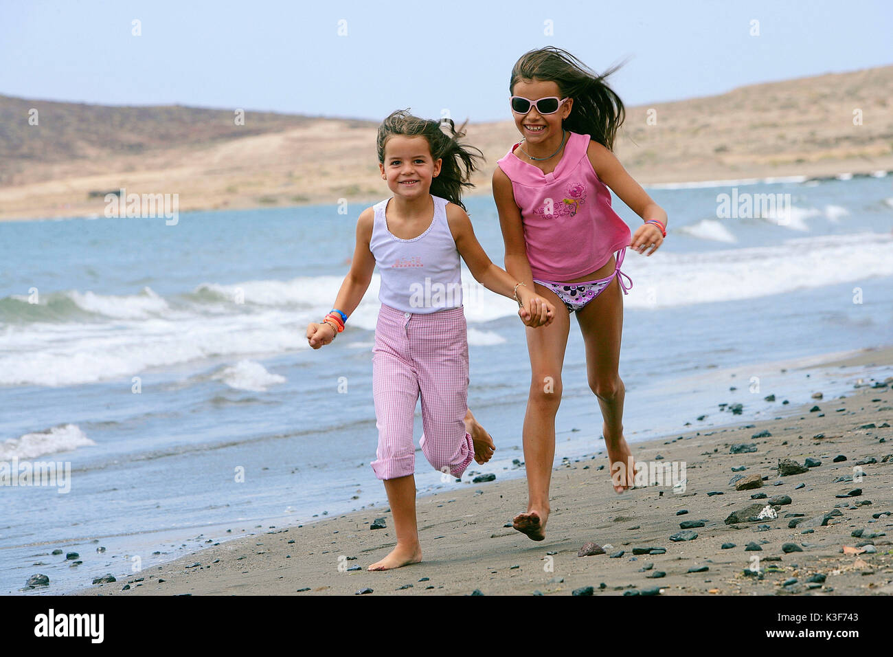 Zwei Mädchen am Strand laufen Stockfoto