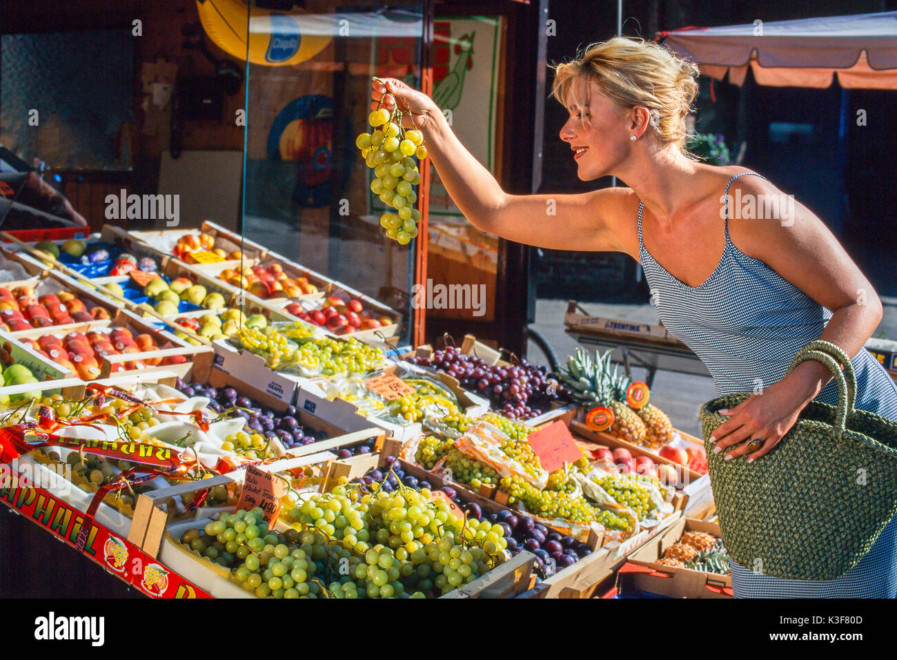 Junge Frau kauft Trauben auf dem Markt in Augsburg Stockfoto