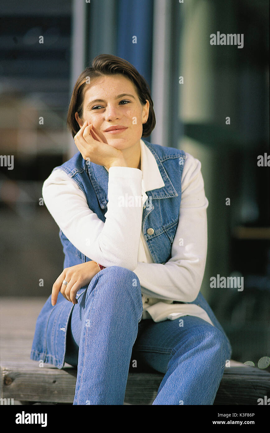 Lächelnde junge Frau lehnt sich auf die Knie Stockfoto