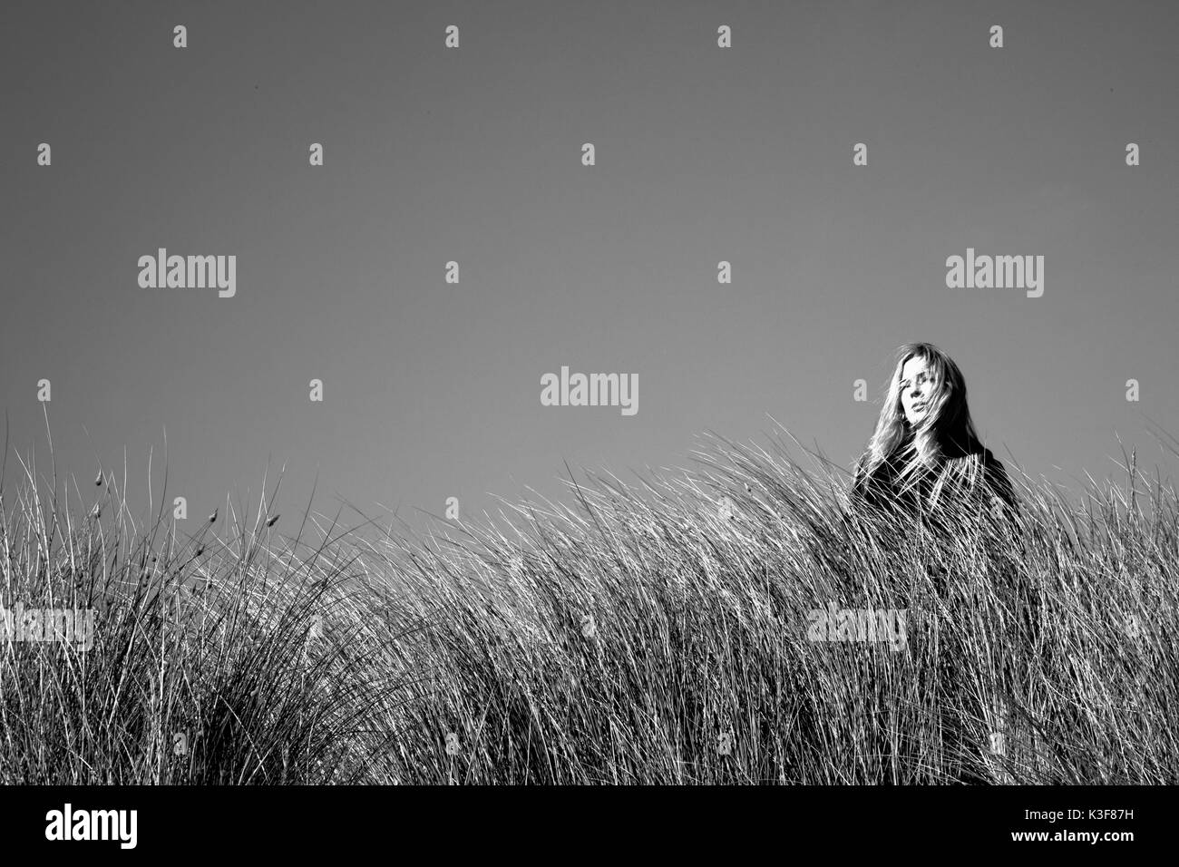 Porträt einer Frau, die unter dem hohen Gras steht Stockfoto