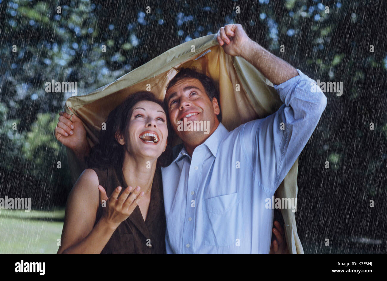 Paar schützt sich mit einer Jacke aus Regen Stockfoto