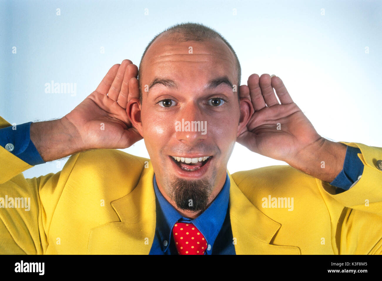 Mann in einem gelben Sport Jacke hält die Hände auf die Ohren Stockfoto