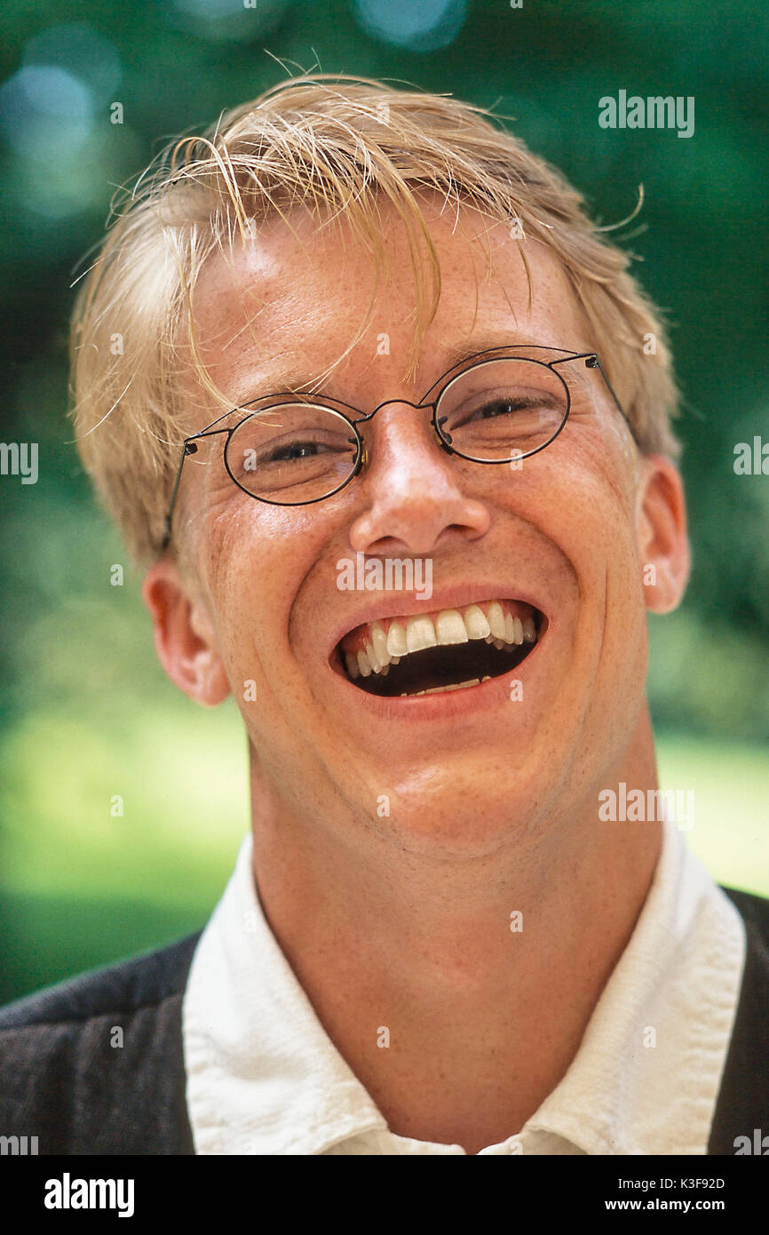 Lachend blonder Mann mit Brille Stockfoto