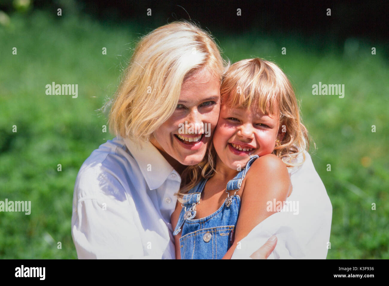 Junge Mutter nimmt Blonde kleine Tochter am Arm Stockfoto