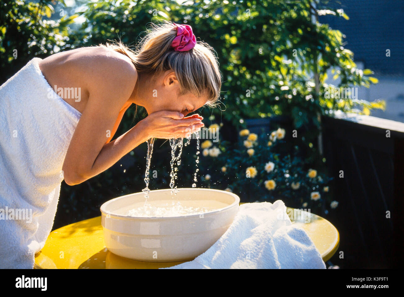 Frau wäscht ihr Gesicht außerhalb Stockfoto