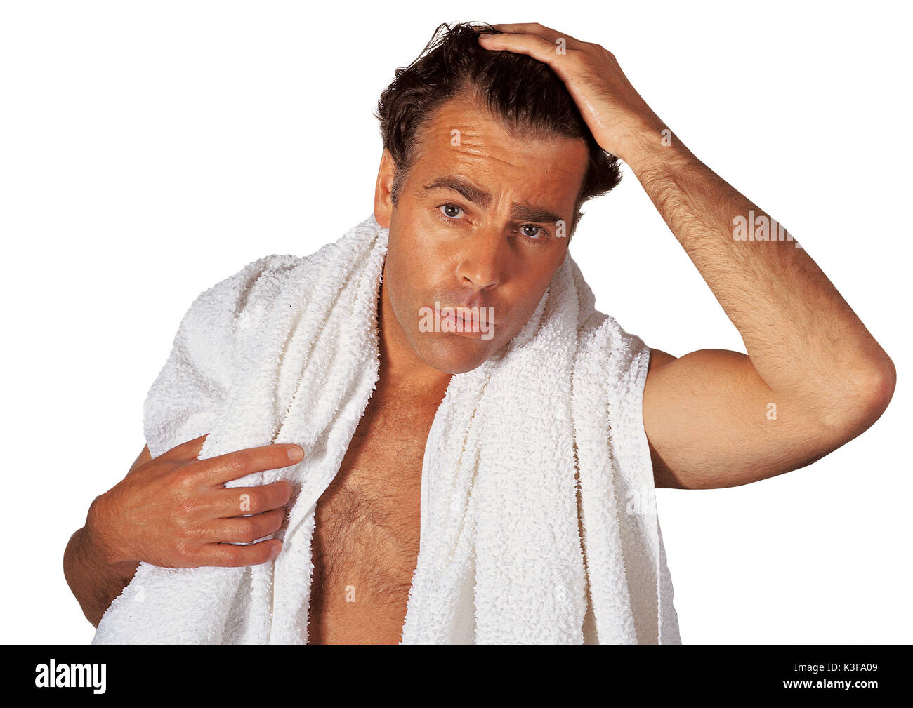 Mann mit Handtuch um die Schultern fährt sich mit der Hand durch die Haare Stockfoto