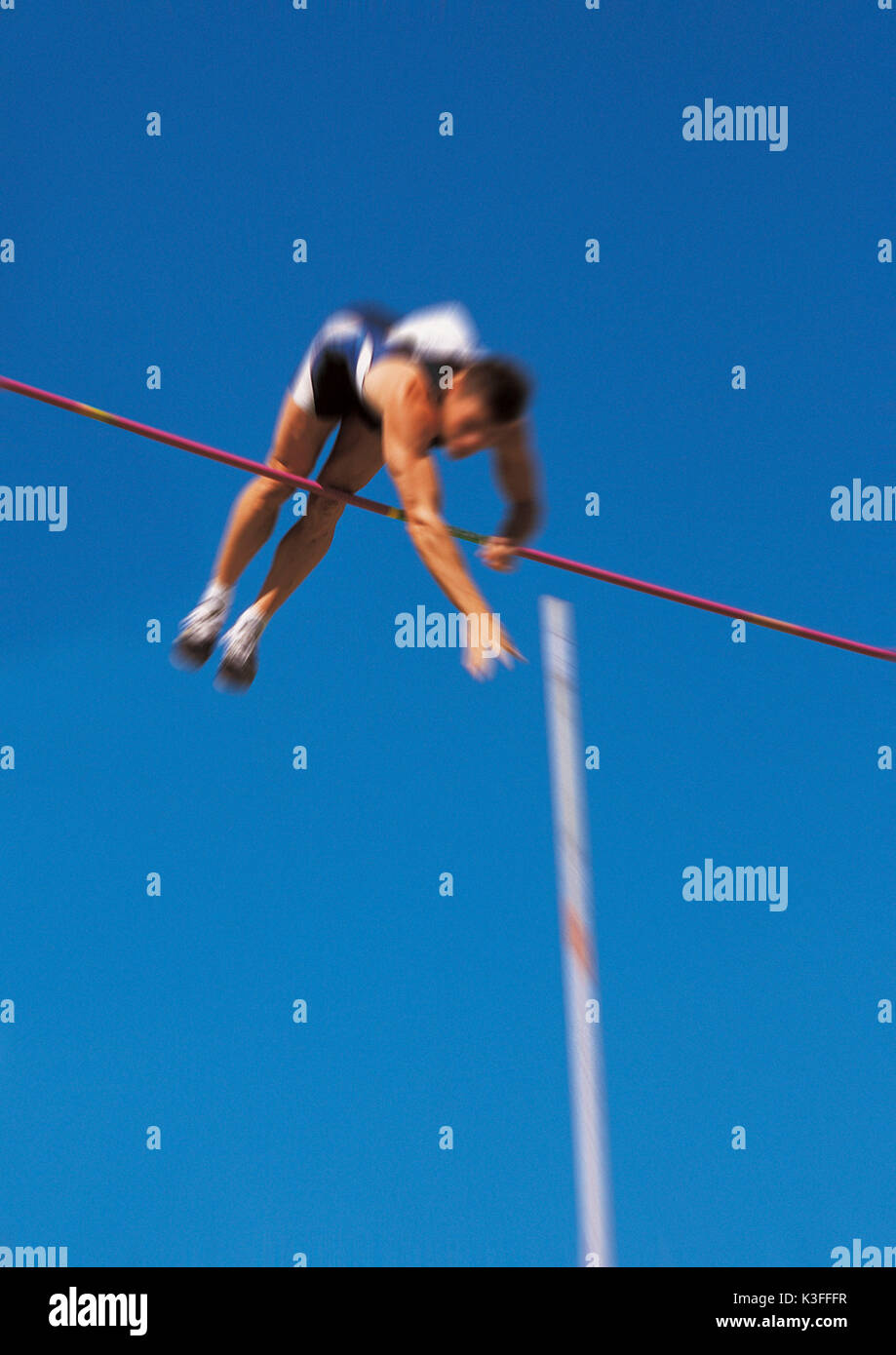 Mann springt über der Bar in der Nähe der Pole Vault Stockfoto