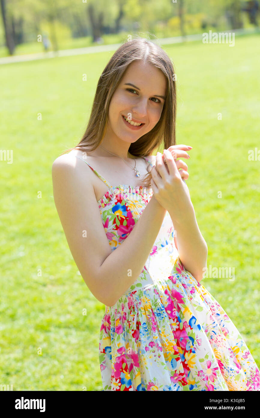 Porträt der jungen schönen Frau mit langem Haar zu tragen Blumen Kleid in grün Spring Park Stockfoto