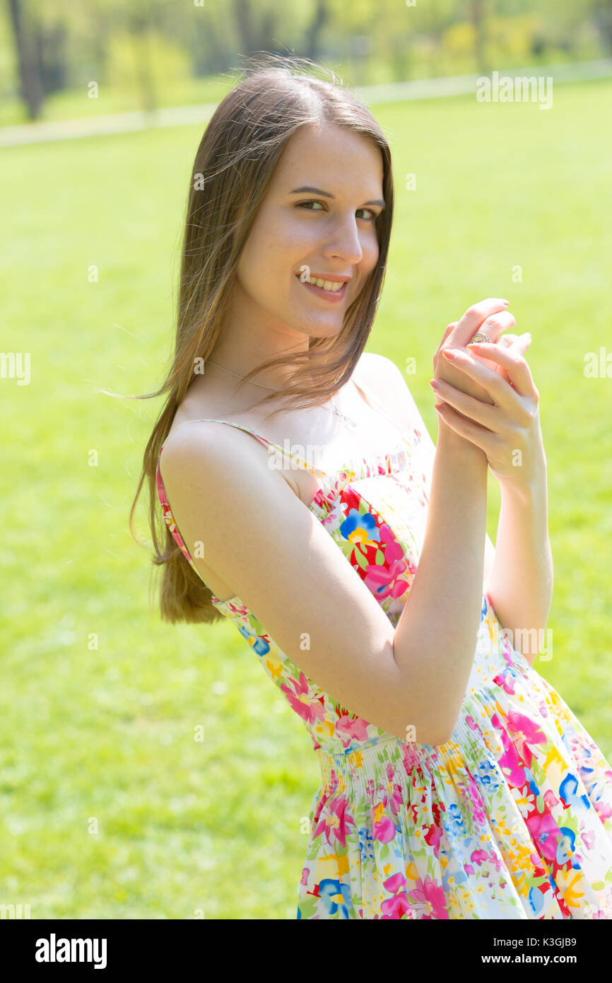 Porträt der jungen schönen Frau mit langem Haar zu tragen Blumen Kleid in grün Spring Park Stockfoto