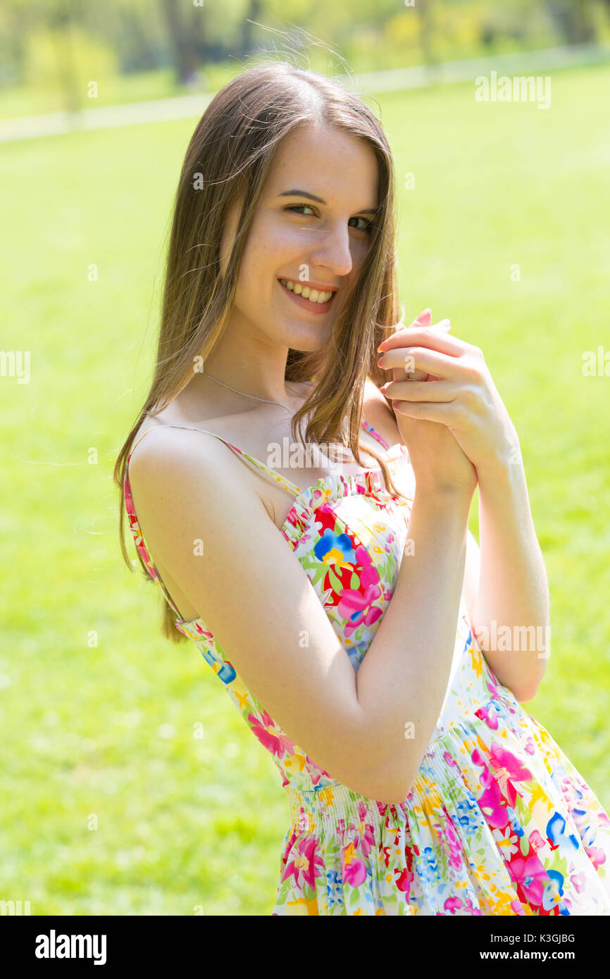 Porträt der jungen schönen Frau mit langem Haar zu tragen Blumen Kleid in grün Spring Park Stockfoto