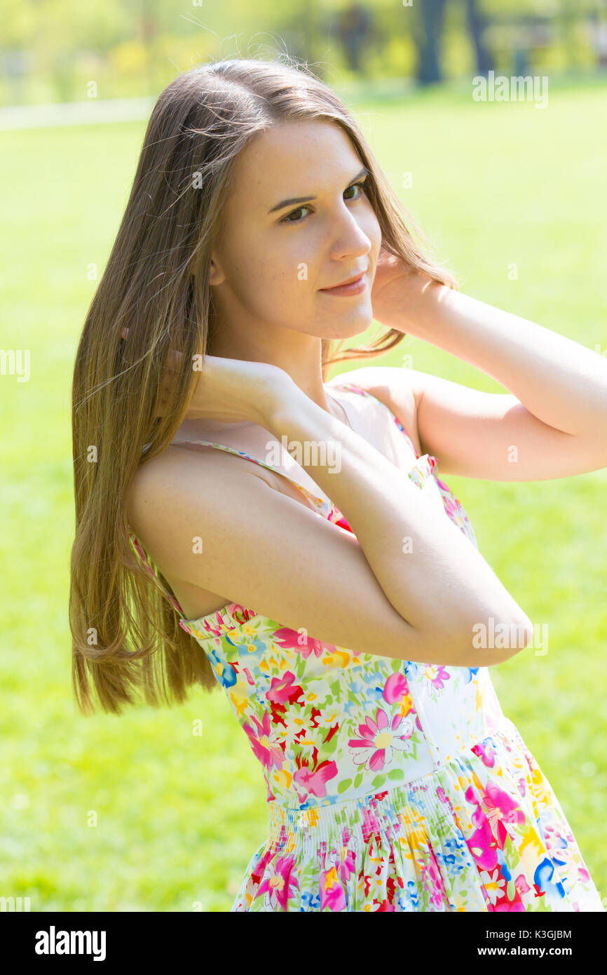 Porträt der jungen schönen Frau mit langem Haar zu tragen Blumen Kleid in grün Spring Park Stockfoto