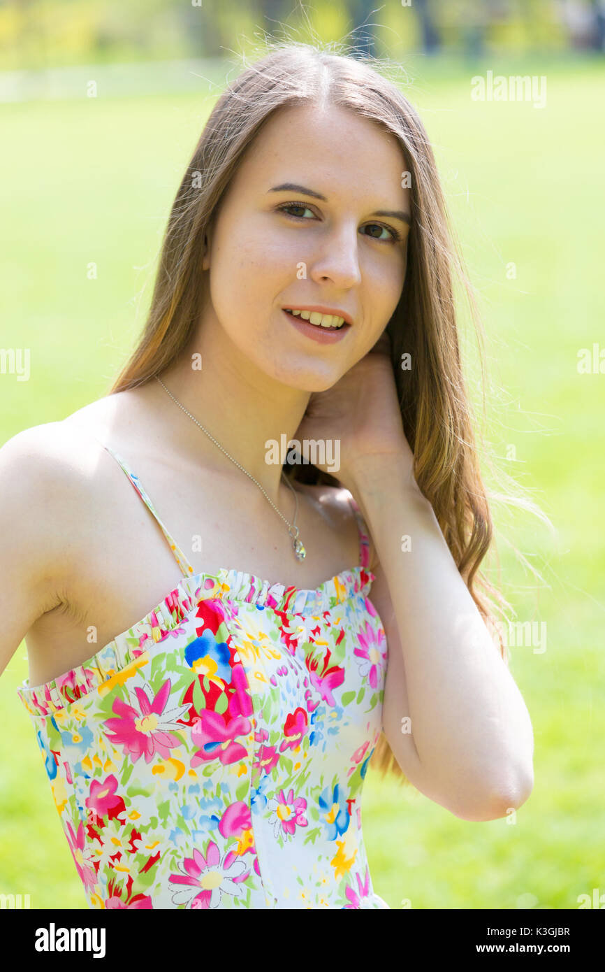 Porträt der jungen schönen Frau mit langem Haar zu tragen Blumen Kleid in grün Spring Park Stockfoto