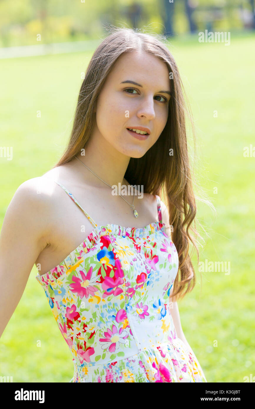 Porträt der jungen schönen Frau mit langem Haar zu tragen Blumen Kleid in grün Spring Park Stockfoto