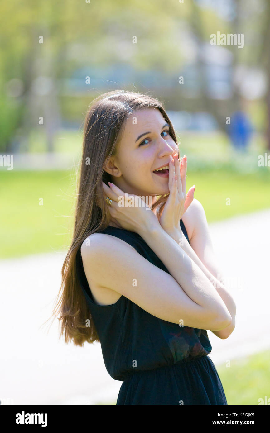 Ein Mädchen in einem Sommer Park ist überrascht und lacht, die Ihren Mund mit Ihrem Palm Stockfoto