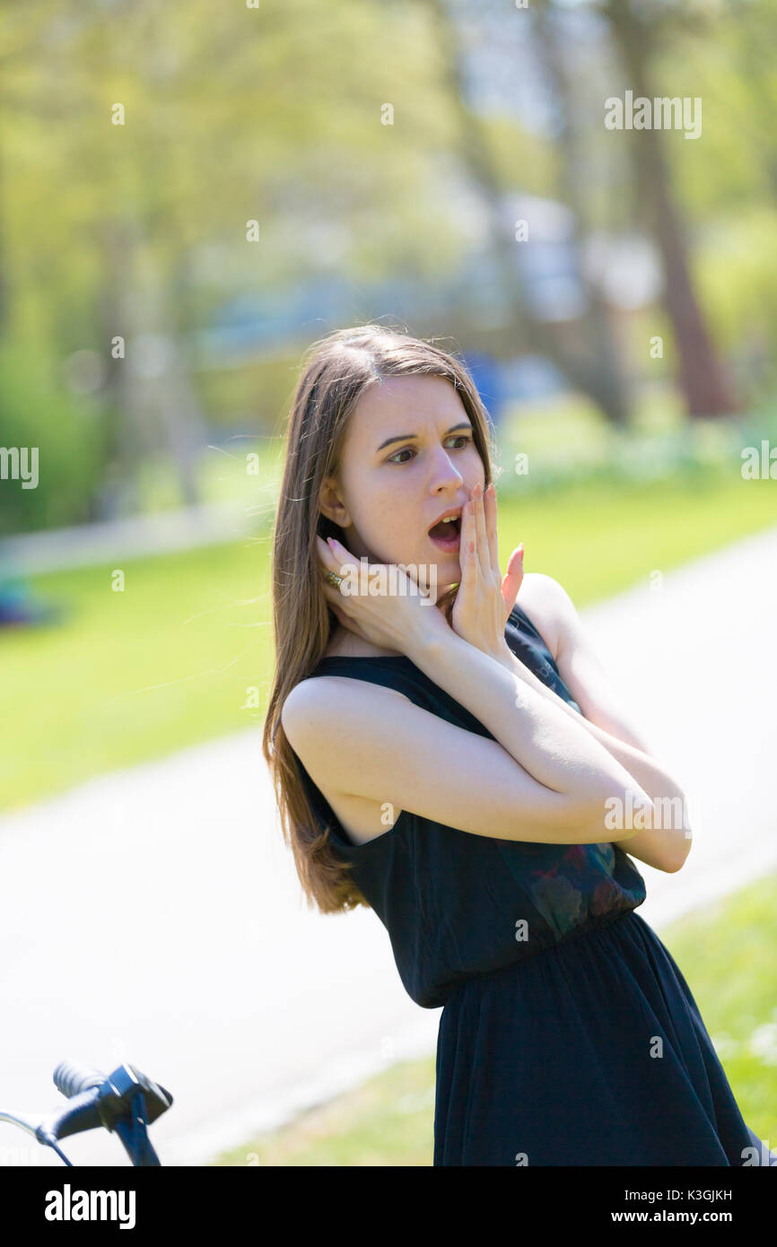 Ein Mädchen in einem Sommer Park ist überrascht und lacht, die Ihren Mund mit Ihrem Palm Stockfoto