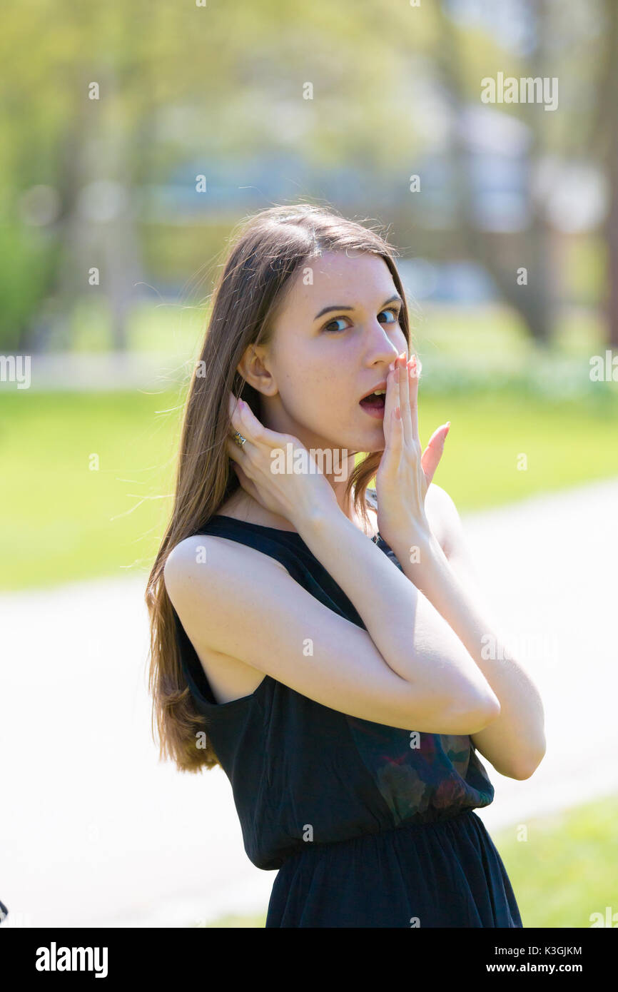 Ein Mädchen in einem Sommer Park ist überrascht und lacht, die Ihren Mund mit Ihrem Palm Stockfoto