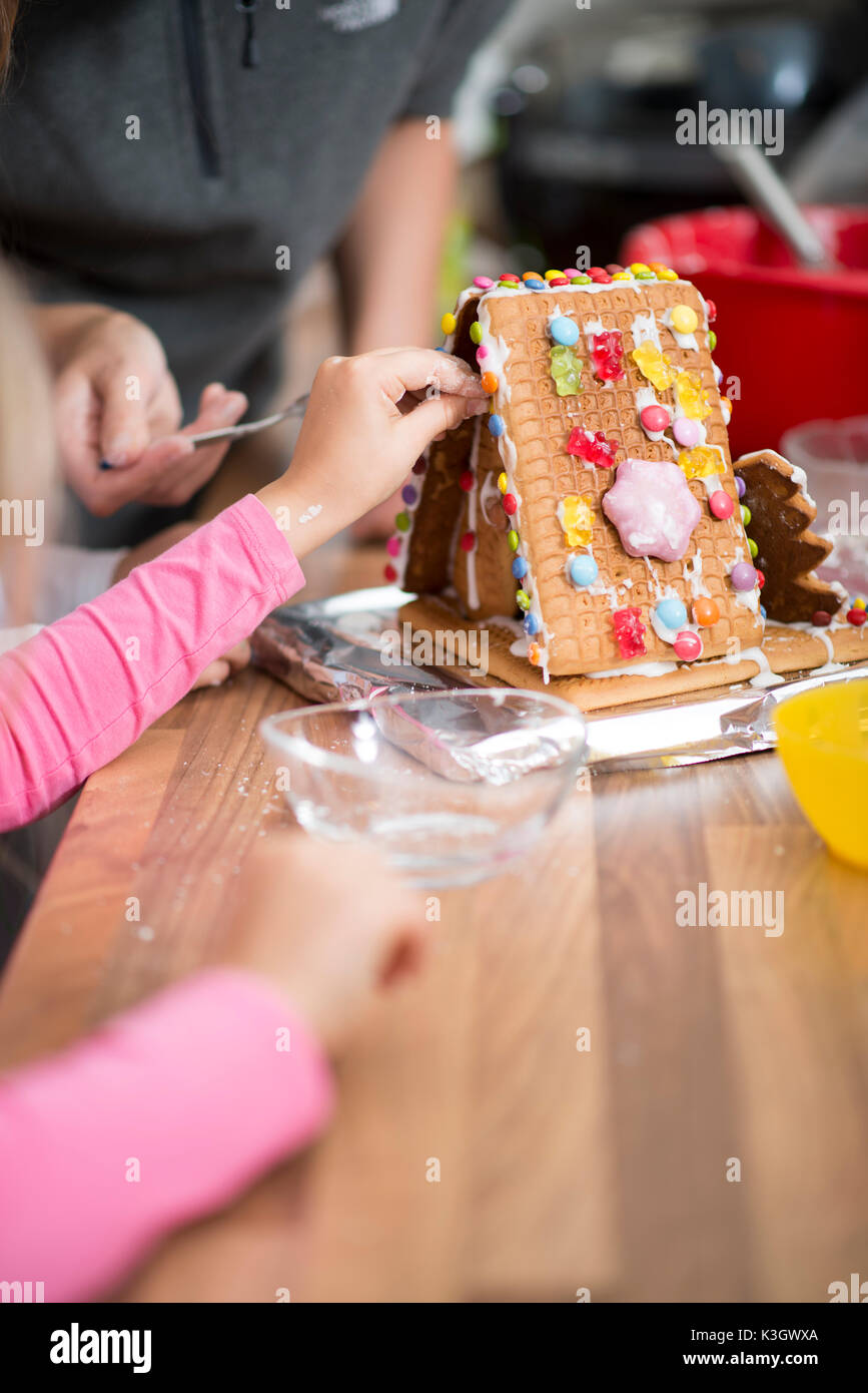 Familie mit Süßigkeiten eine hausgemachte Lebkuchen Haus dekoriert Stockfoto