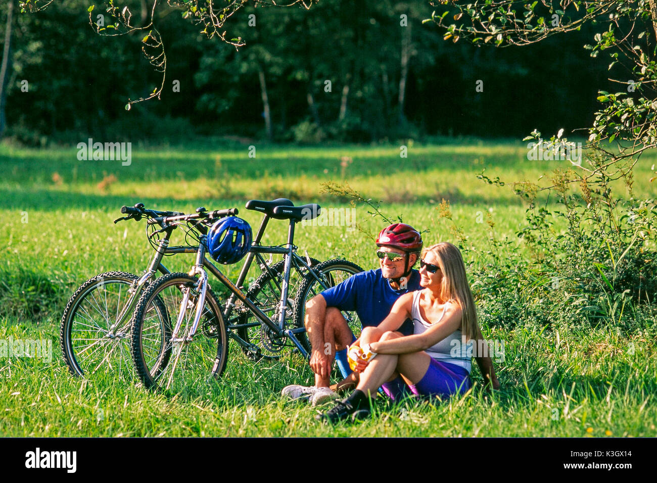 Paar in der Nähe Mountainbikes macht Pause auf einer Wiese Stockfoto