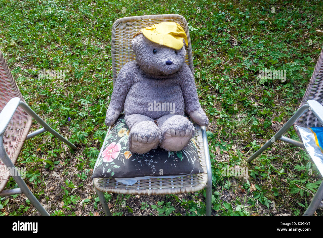 Ein alter Teddybär Urlaub sitzt auf einem Stuhl in Ein Garten Stockfoto