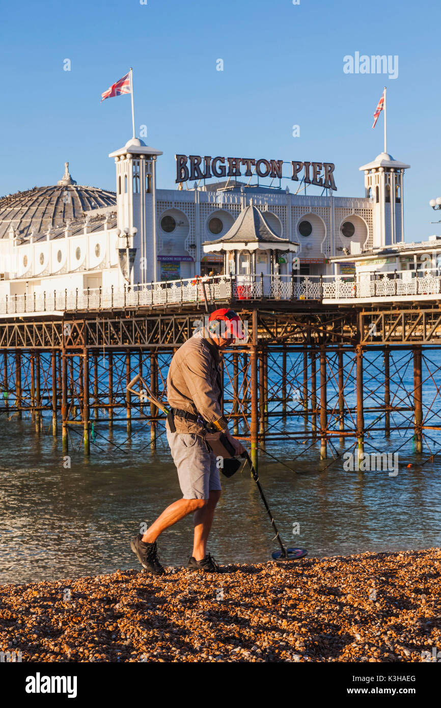 England, East Sussex, Brighton, Mann mit Metalldetektor am Strand und Pier von Brighton Stockfoto
