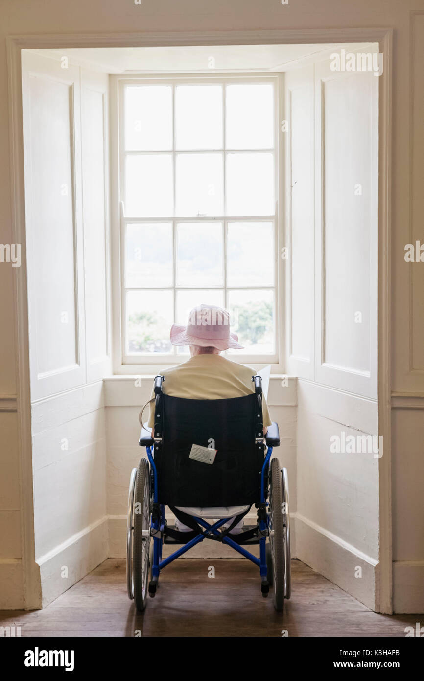 England, ältere Dame im Rollstuhl Blick aus Fenster Stockfoto