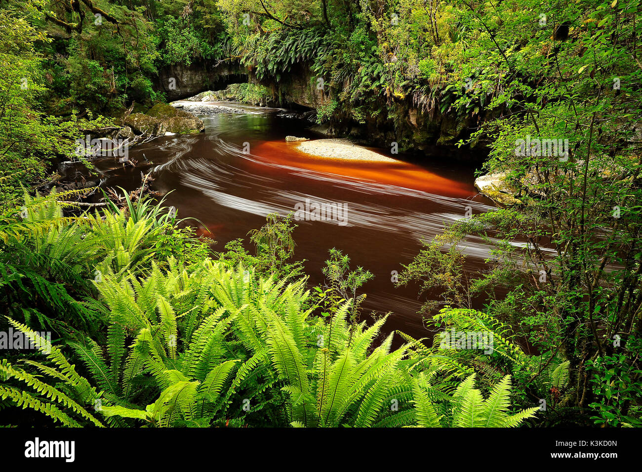 Die upite Becken Bögen sind ein Ort von Interesse mit dem idyllischen Dorf karamea an der Westküste der Südinsel von Neuseeland. Braunes Wasser mit weißer Schaum schlängelt sich durch dichten tropischen Dschungel unter den berühmten upite rock Bögen Stockfoto