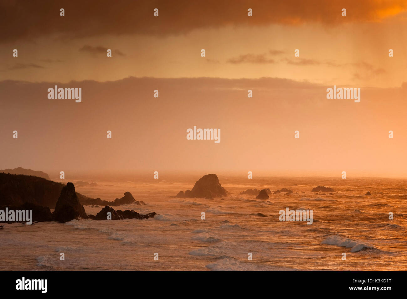 Felsformationen im Pazifik im letzten Abendlicht. Leichter Regen kommt von der Wolke, und unter den harten surf Überspannungen bis zu den Klippen von der Neuseeländischen Küste. Stockfoto