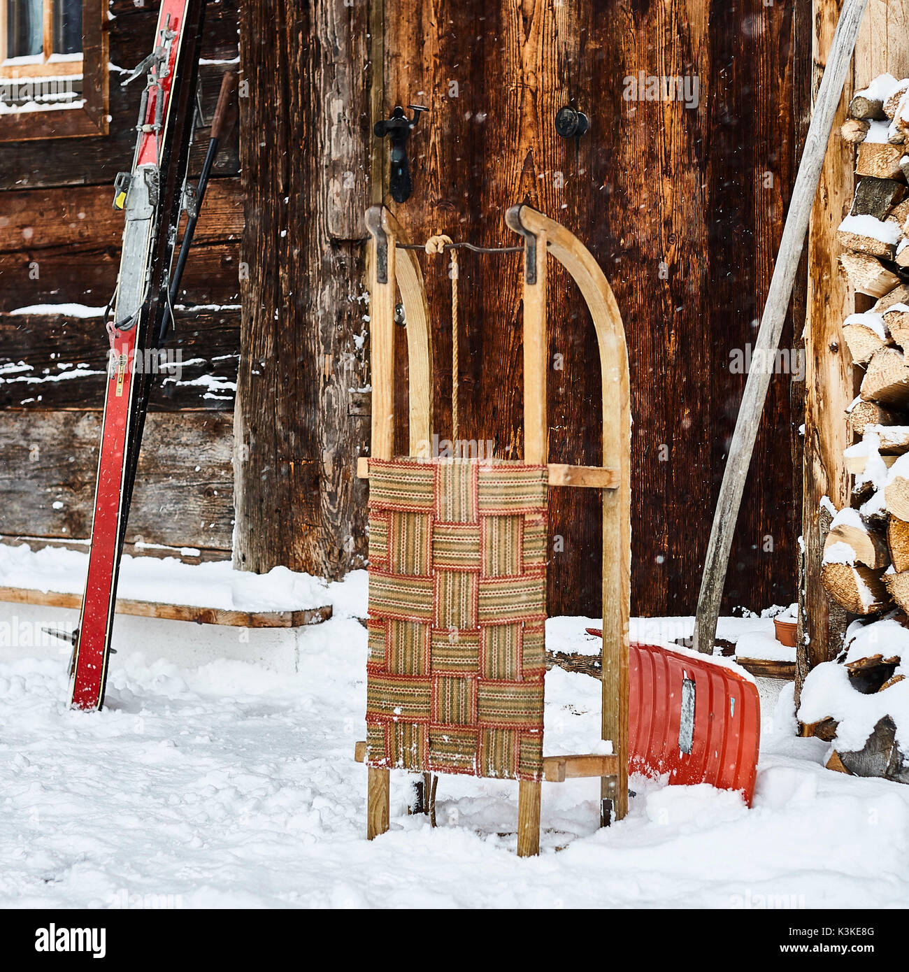 Alte Tür, nostalgische Skier, Schlitten, Schnee schaufeln, Schneefall, Stockfoto