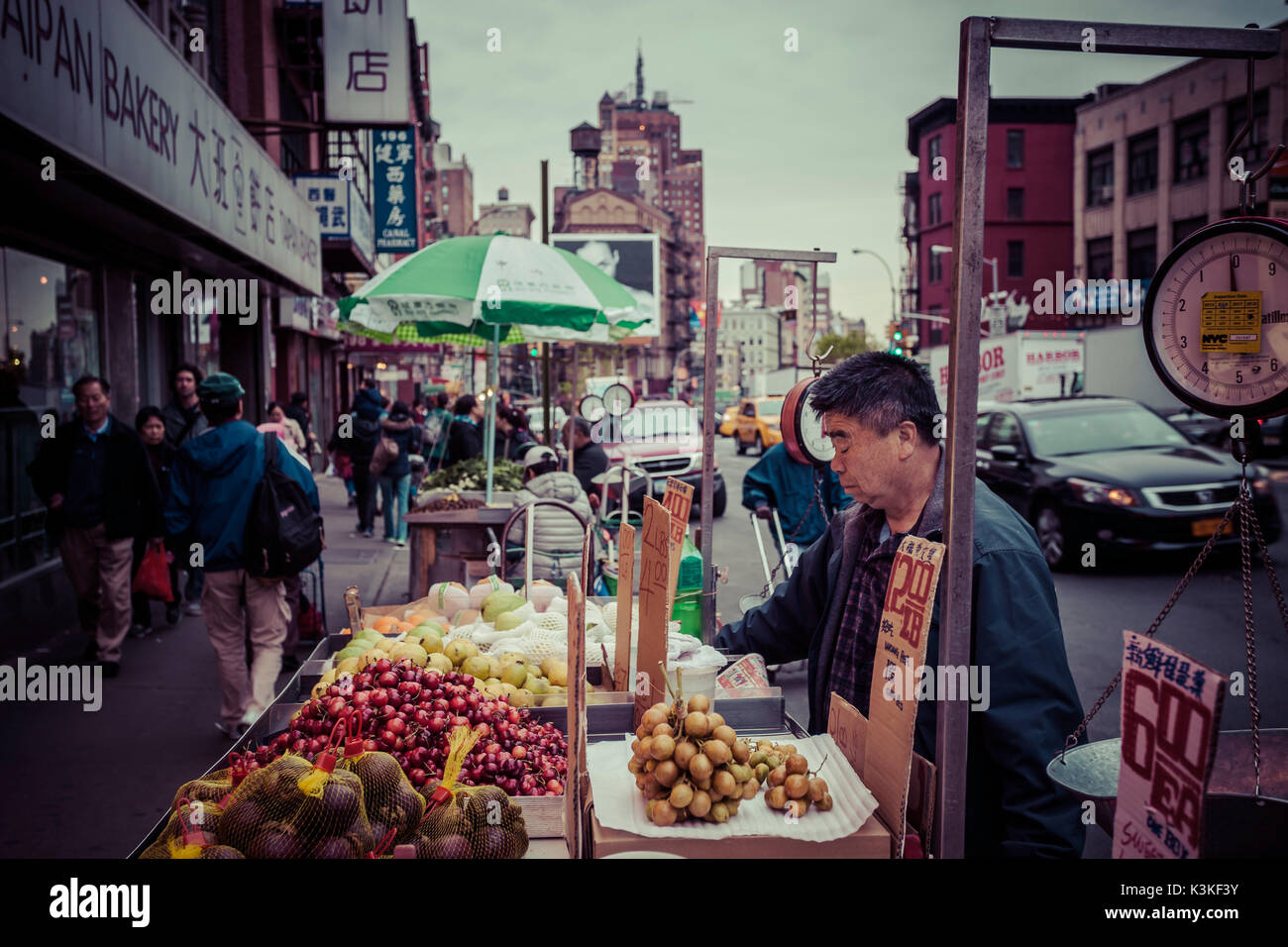 Eine Frucht Marktstand und Straßenbild mit Autos und Fußgängern in Chinatown, Manhatten, New York, USA Stockfoto