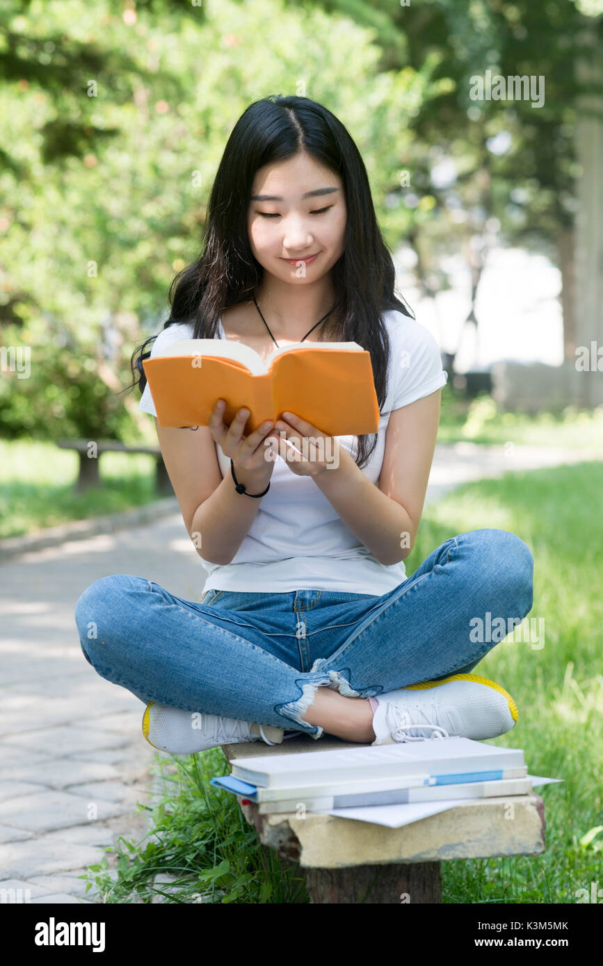 Portrait von College Mädchen Bücher lesen mit Sitzen im Park Stockfoto