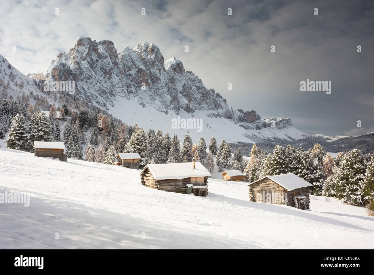 Ein Winter Blick auf den Naturpark Puez Geisler in Villnöss mit einigen Hütten im Vordergrund und im Hintergrund die Geisler, Provinz Bozen, Südtirol, Trentino Alto Adige, Italien, Europa Stockfoto