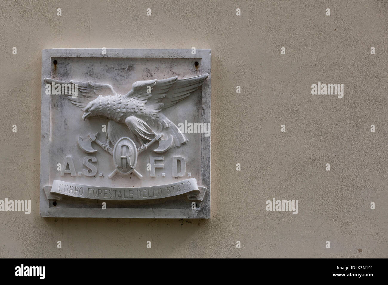 Marmor bas-relief mit dem alten Symbol der staatlichen Forstwirtschaft Korps, die mit den Buchstaben A.S.F.D. die Abkürzung für'Azienda di Stato delle Foreste Demaniali". Die Plakette hängt außerhalb in der Nähe von Case Salet, Nationalpark der Dolomiten von Belluno Stockfoto