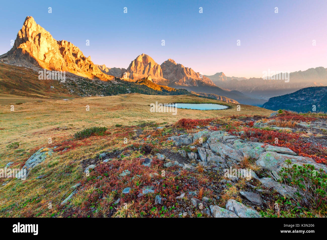 Herbst Sonnenaufgang in der Nähe von Passo Giau zu den Ampezzaner Tal. Die blaubeere Pflanzen sind rot und Gras wird durch die ersten Fröste verbrannt. Die Sonne beleuchtet die Gusela und Tofane. Dolomiten, Italien Stockfoto