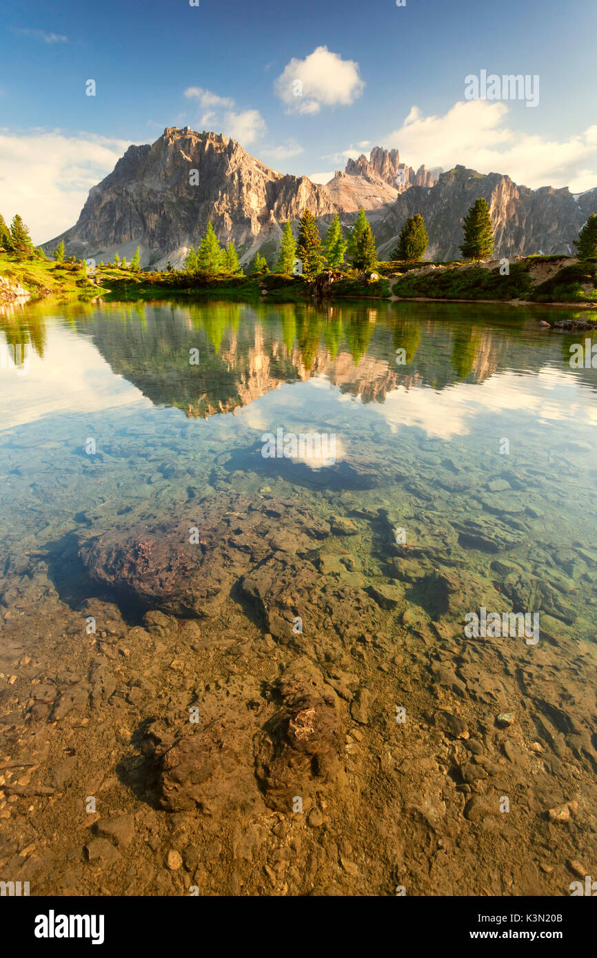 Die kleinen alpinen See Limedes in ein Morgen im Frühsommer. Lärchen und Tannen mit ihren leuchtenden Farben zeichnen sich im Gegensatz zu den Wänden der Lagazuoi noch teilweise im Schatten. Dolomiten, Passo Falzarego. Stockfoto