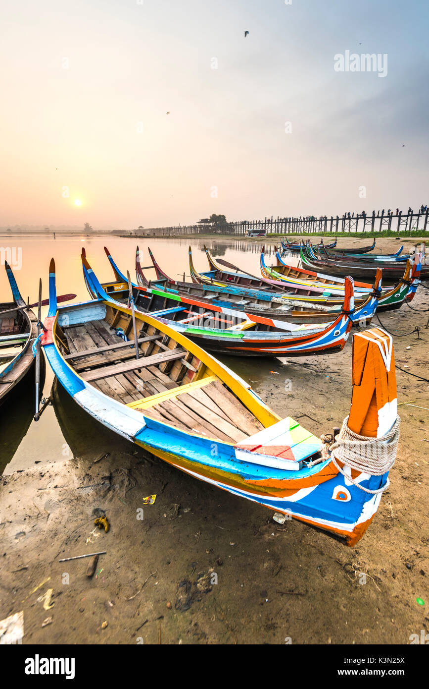 Amarapura, Mandalay, Myanmar. Bunte Boote am Ufer des Taungthaman See bei Sonnenaufgang, mit der U-Bein Bridge im Hintergrund. Stockfoto