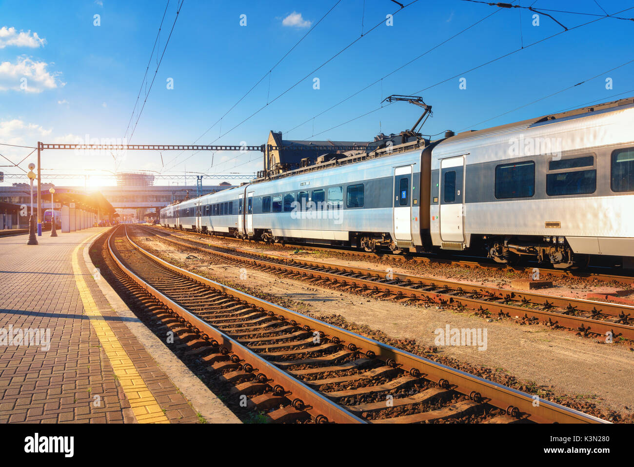 Schöne Personenzug am Bahnhof bei Sonnenuntergang. Gewerbliche Anzeigen mit modernen Intercity Zug, Bahn, Bahnsteig und blauer Himmel in Th Stockfoto