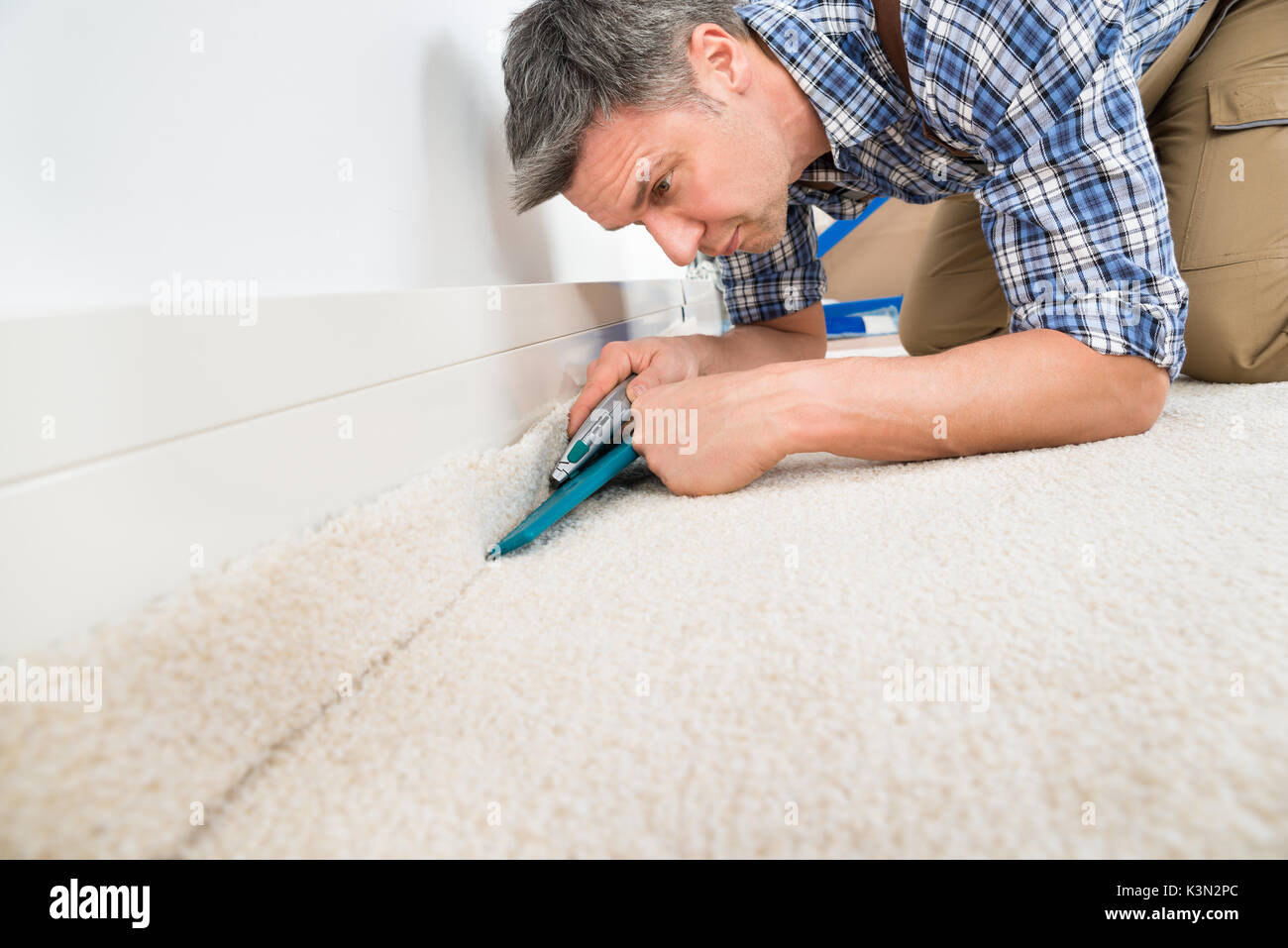 Nahaufnahme eines Handwerkers Einbau Teppich auf dem Boden Stockfoto