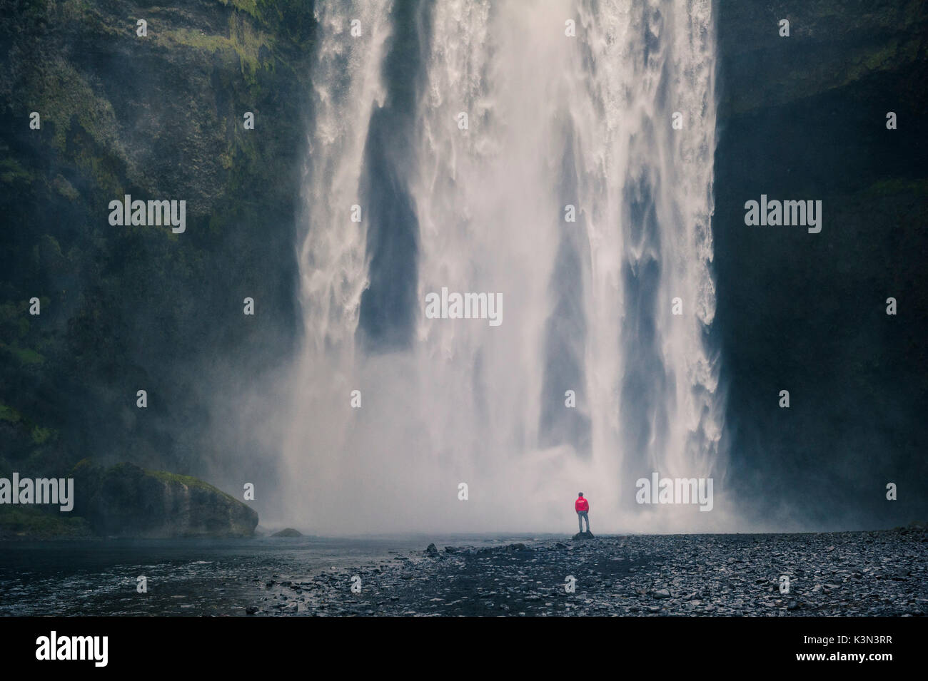 Südlichen Island. Mann steht unter dem Wasserfall Skogafoss. Stockfoto