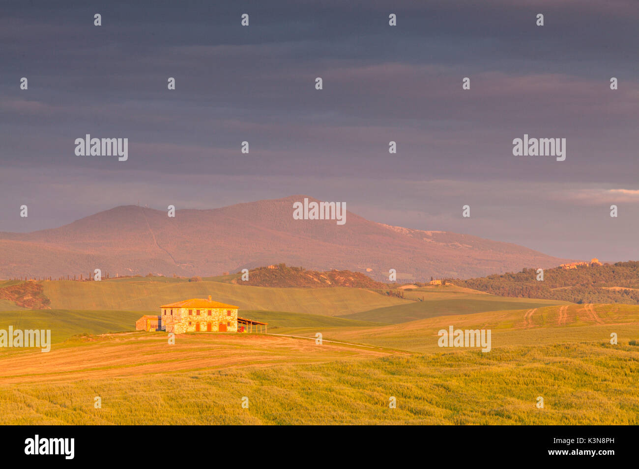 Gallina, Val d'Orcia, Toskana, Italien. Die Sonne schafft es, Peep durch die dicken Wolken und leuchtet bei Sonnenuntergang ein altes Bauernhaus Stockfoto