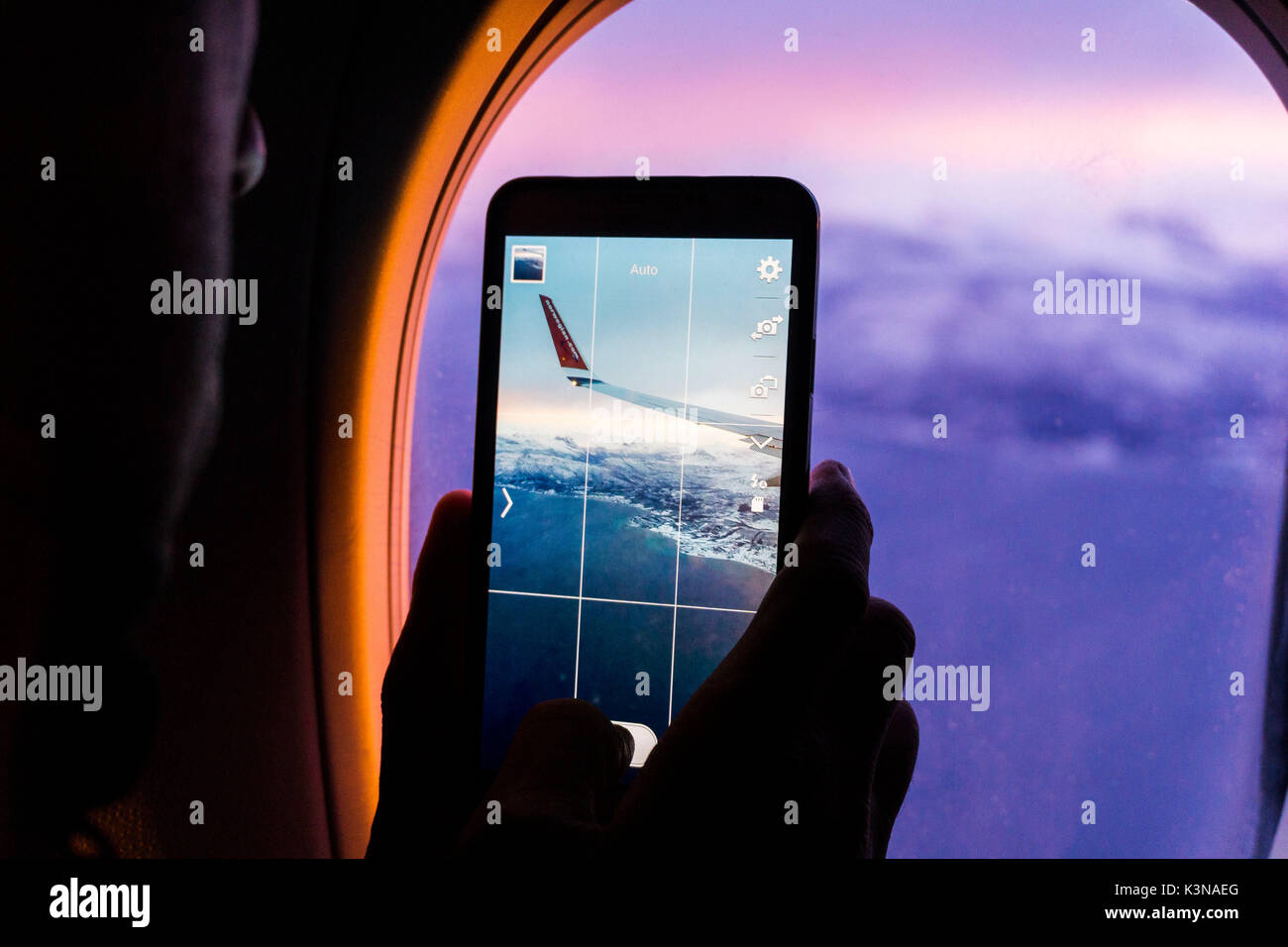 Norwegen, Lofoten, Silhouette eines Mannes Fotos von Bergen und Flügel mit einem Smartphone aus einem fliegenden Flugzeug über das Fenster Stockfoto