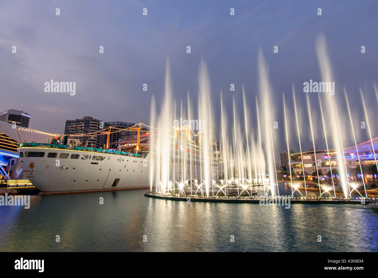 Tanzenden Fontänen in neuen Sea World Plaza, einem der Wahrzeichen von Shenzhen, bei Sonnenuntergang mit der Minghua Schiff auf der Mitte. Das Schiff wurde ursprünglich als Anceevilla bekannt und wurde später umbenannt in 'Minghua" durch die Chinesen, die es kaufte, China Stockfoto