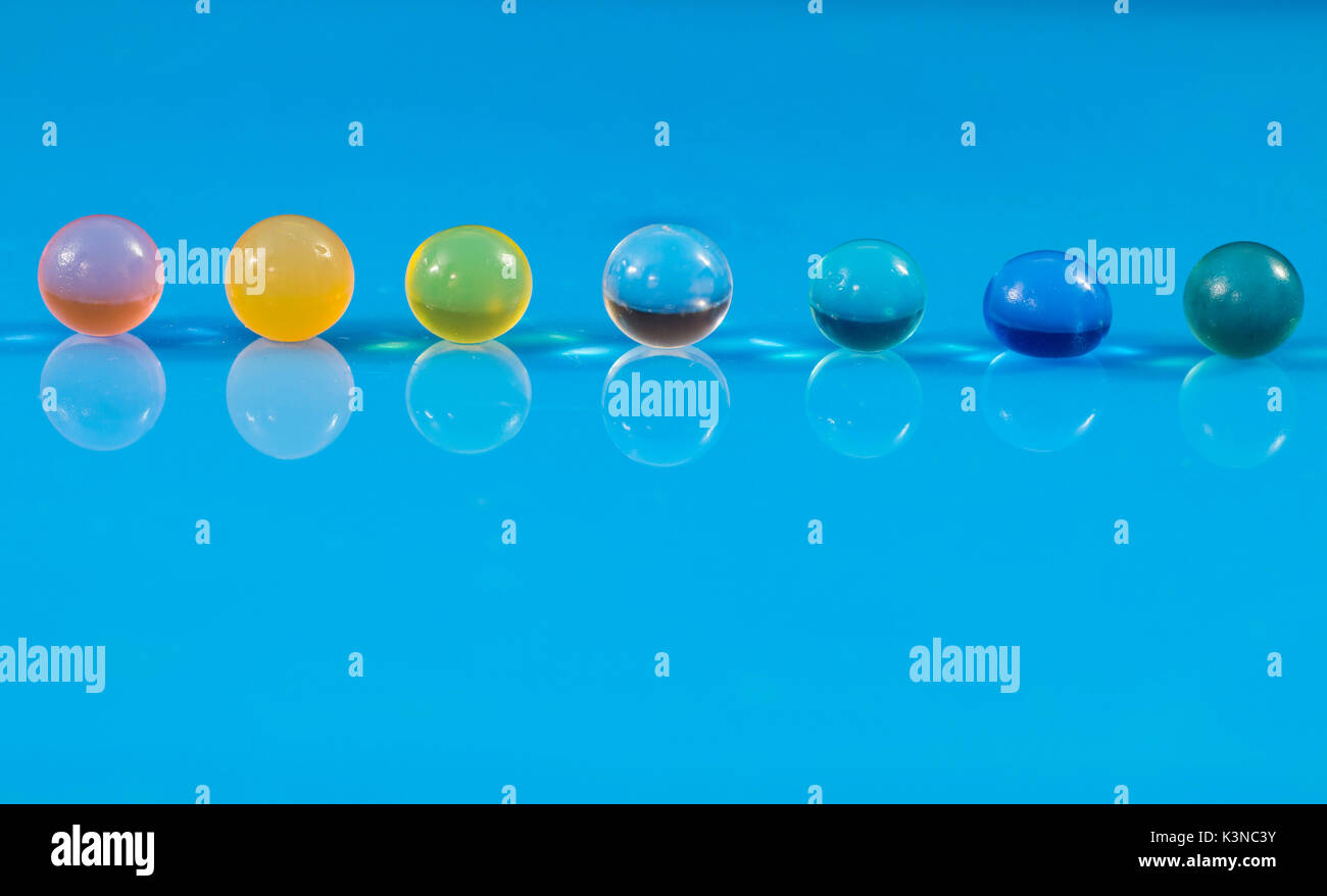 Reihe von farbigen jelly Sphären über einer reflektierenden Ebene, in einem noch leben Zusammensetzung Stockfoto