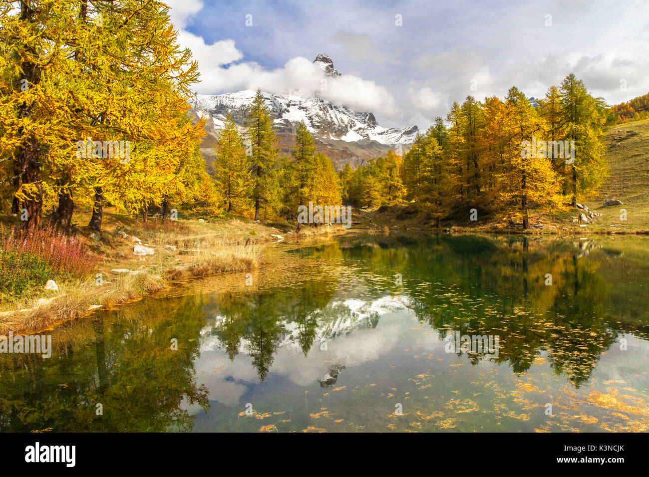 Das Matterhorn steht unter den Wolken und es ist in dem kleinen See Blu umgeben von bunten Bäume im Herbst (Cervinia Valtournenche, Provinz Aosta, Aostatal, Italien, Europa). Stockfoto